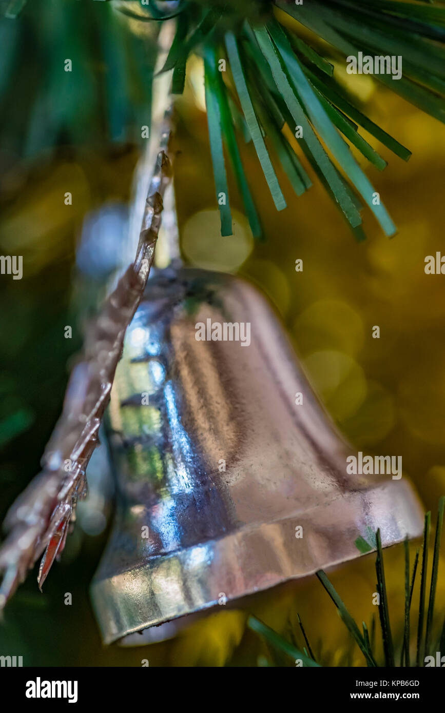 Primo piano della vecchia argento ornamento di Natale sulla struttura ad albero. Albero di natale di picchi e campana di argento decorazione, golden bokeh di fondo. Foto Stock