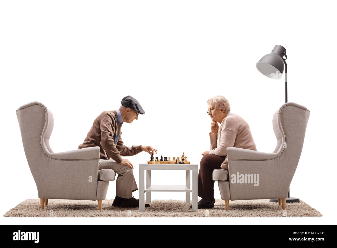 Uomo anziano e una donna anziana seduti in poltrona a giocare una partita a scacchi isolati su sfondo bianco Foto Stock