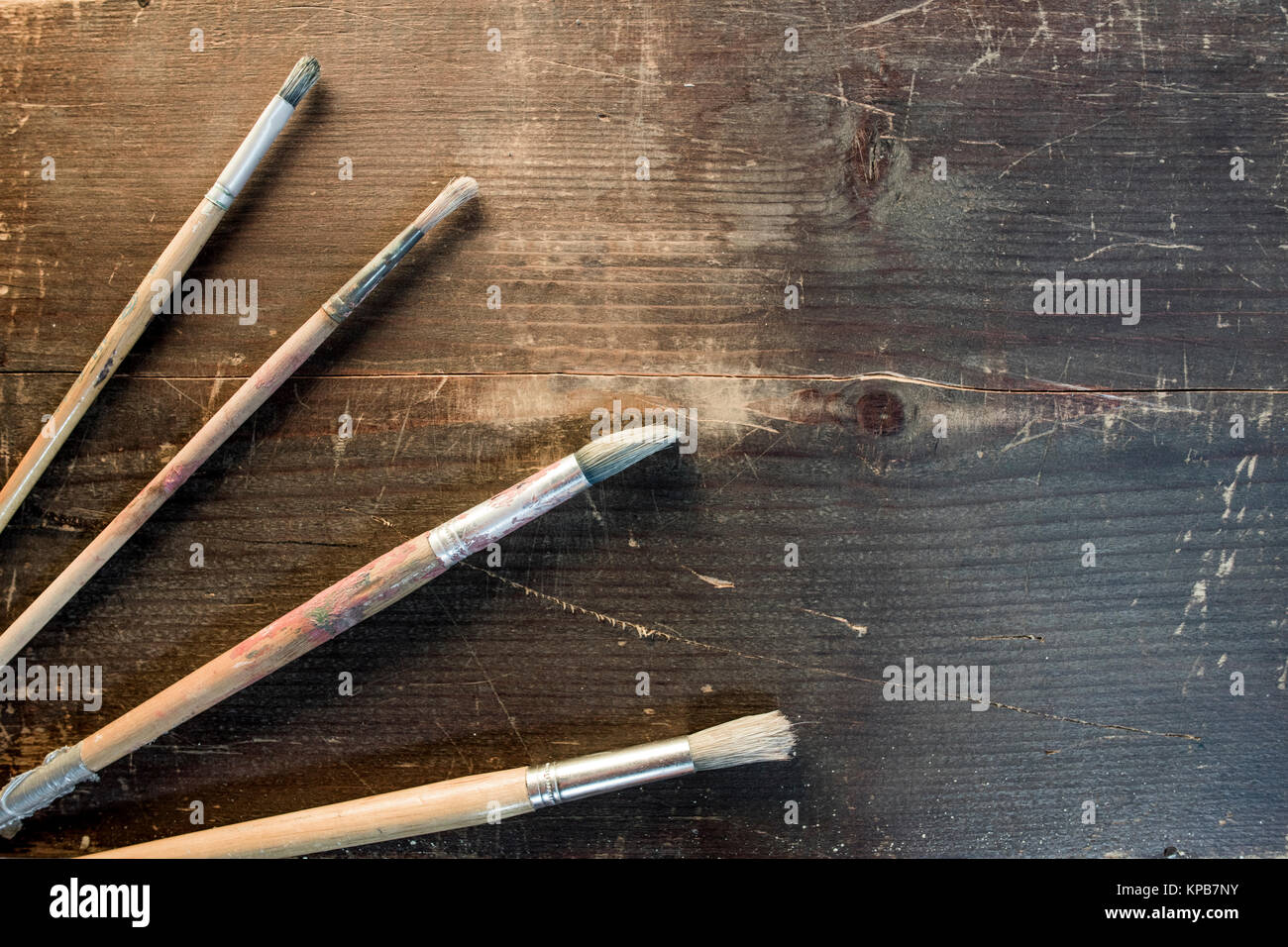 spazzole di vernice di quattro dimensioni che si stendono su di una tavola di legno sfondo Foto Stock