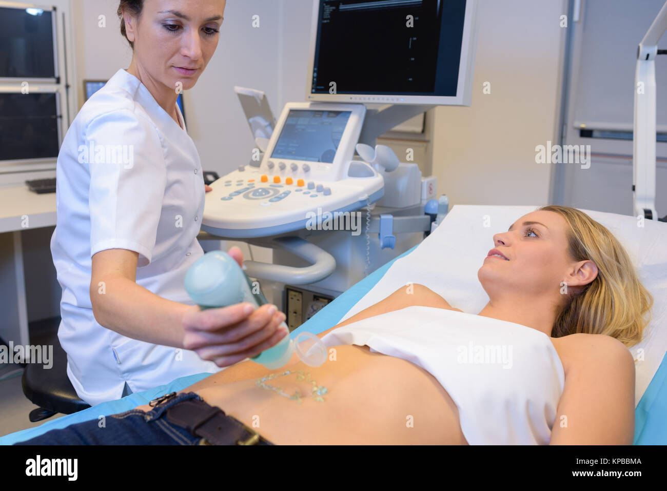 Medico di applicare il gel lubrificante alla donna di addome Foto Stock