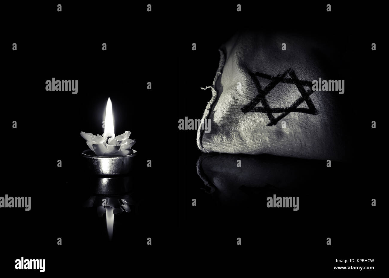 La stella di Davide e la candela si erge sulla tavola su uno sfondo nero in memoria delle vittime dell'Olocausto e il genocidio. Bianco nero photo Foto Stock