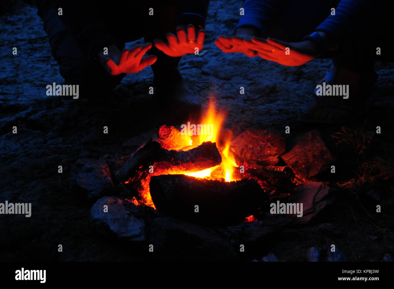 Due camper riscalda le loro mani su un fuoco di notte. Foto Stock