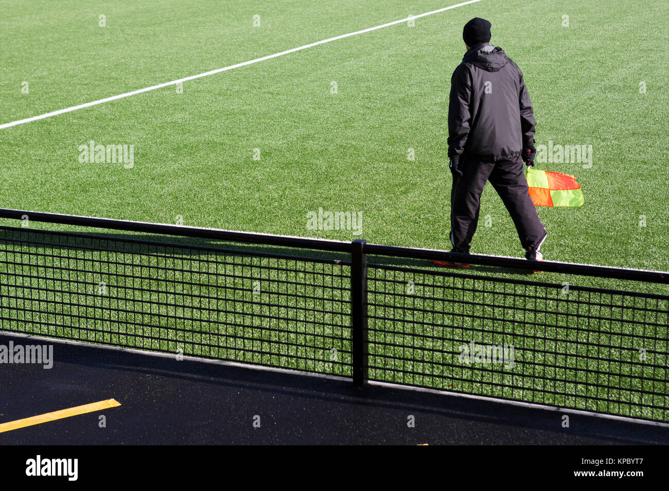 Una partita ufficiale, il per guardafili, camminando lungo il bordo di una nuova erba artificiale passo portando la sua bandiera. Foto Stock