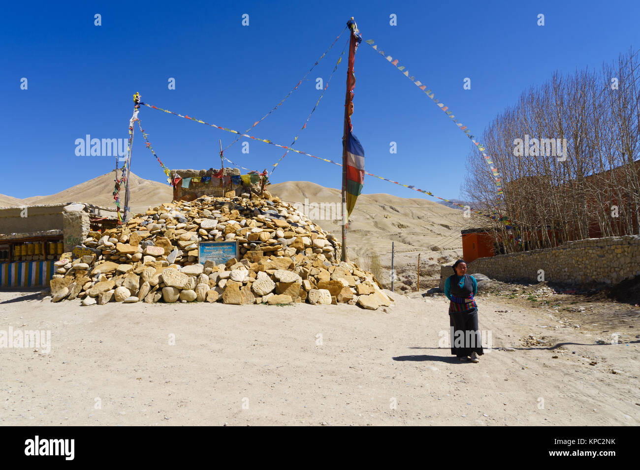 Il Tibetano donna camminare davanti a un mucchio di pietre a pregare in Lo Manthang, Mustang Superiore regione, Nepal. Foto Stock