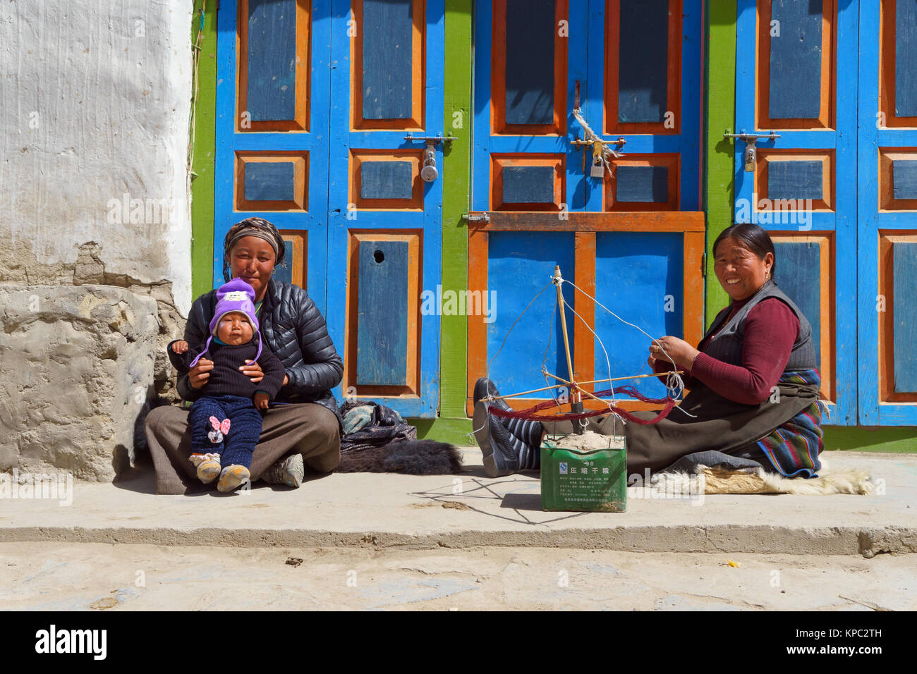 I giovani tibetani azienda madre suo figlio accanto a una donna più anziana che è la filatura Himalayan lana di pecora, Lo Manthang, Mustang Superiore regione, Nepal. Foto Stock