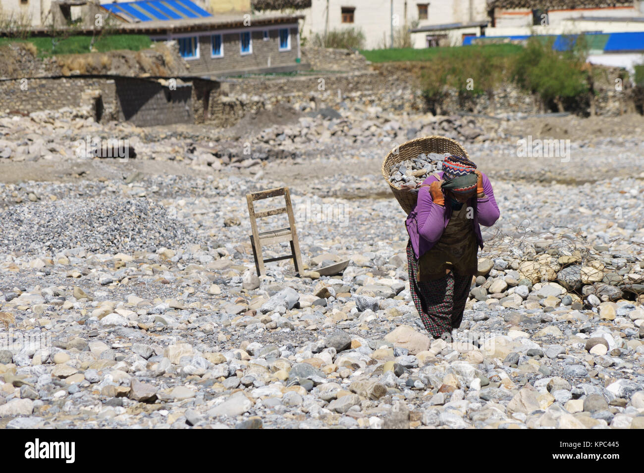 Forte donna Nepalese che trasportano un cestello riempito con pietre essa si romperà con un martello per la costruzione. Foto Stock