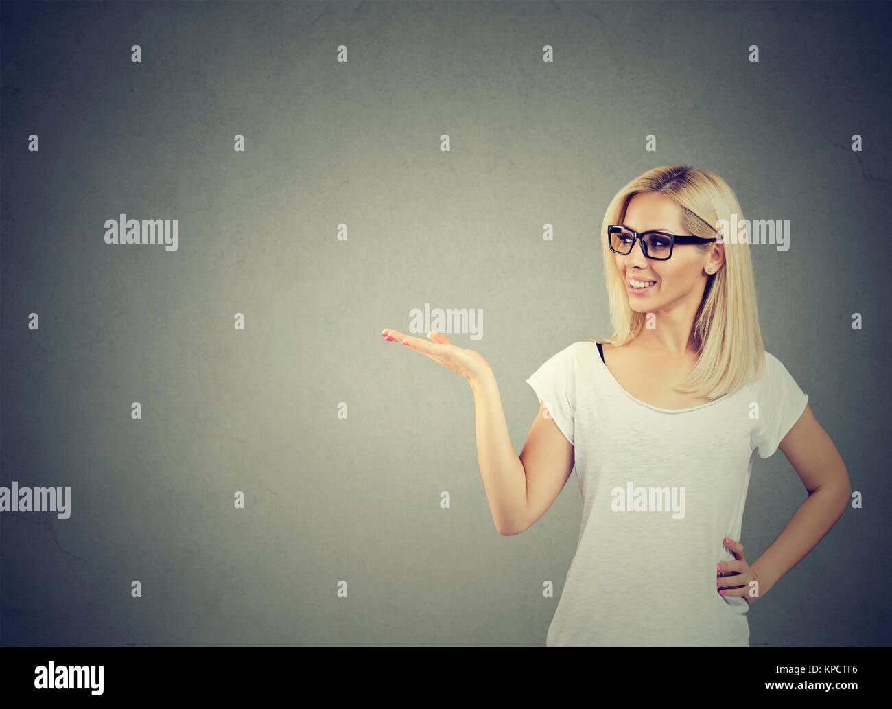 Modello di giovane azienda palm fino presentare qualcosa allegramente sul grigio. Foto Stock