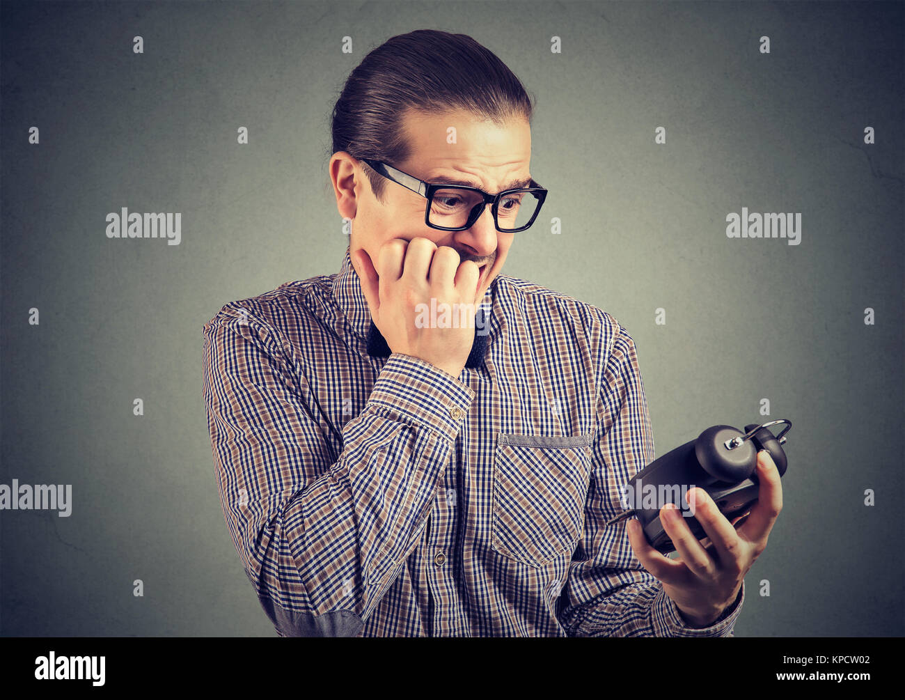 Giovane uomo in occhiali cercando nervosamente a orologio pressione sensazione di mancanza di tempo. Foto Stock