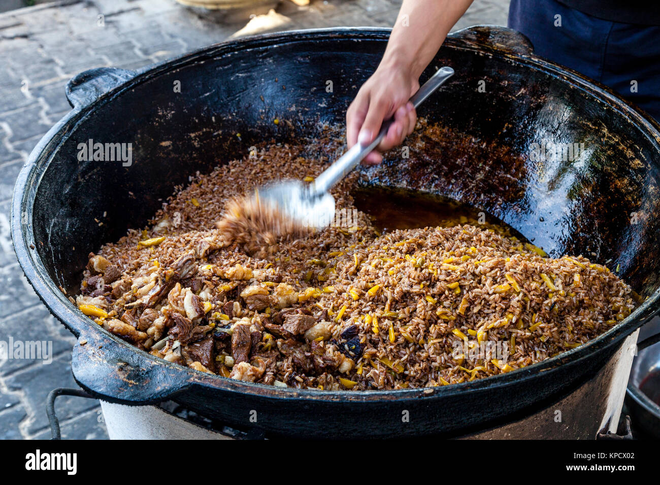 Un uomo cuochi riso per il plov (il piatto nazionale) presso l'Asia Centrale del centro di Plov, Tashkent, Uzbekistan Foto Stock