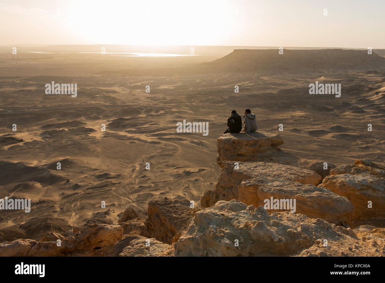 Due ragazzi guardando il tramonto dalla cima del Gebel Dist, con una vista sul lago di el-Marun Foto Stock