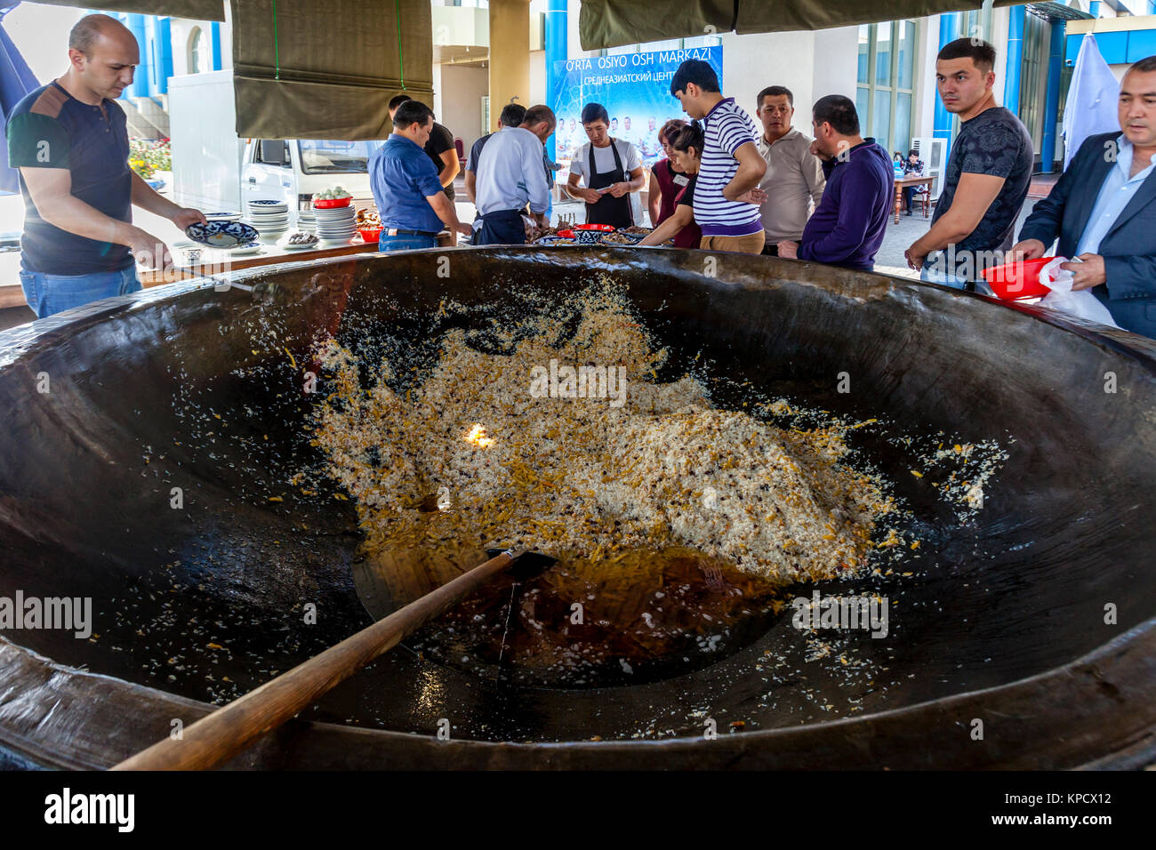 Servire gli uomini PLOV (il piatto nazionale) da un grande calderone presso l'Asia Centrale del centro di Plov, Tashkent, Uzbekistan Foto Stock