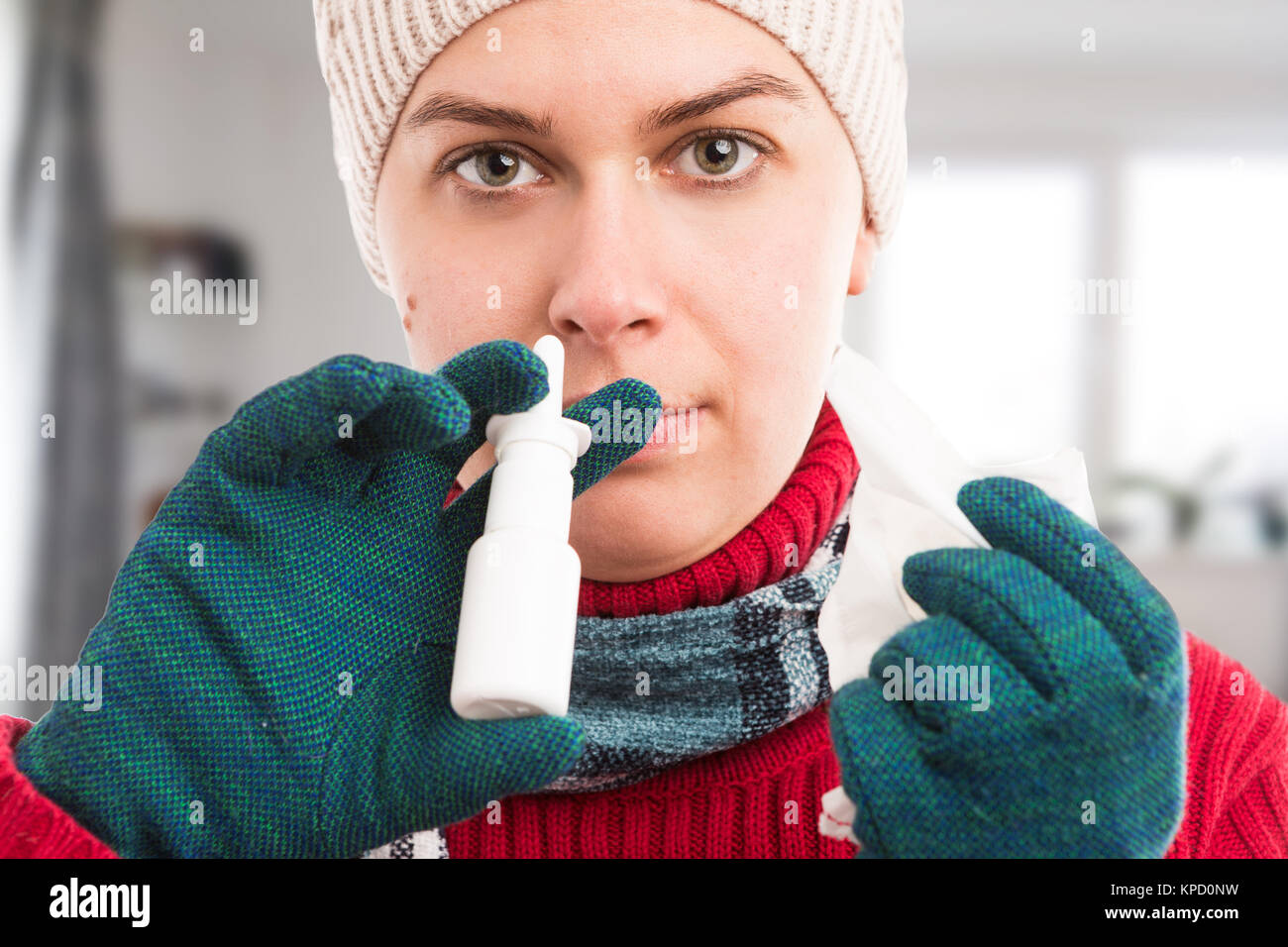 La donna a freddo utilizzando uno spray nasale a casa come influenza o il concetto di influenza e tenendo un tessuto Foto Stock