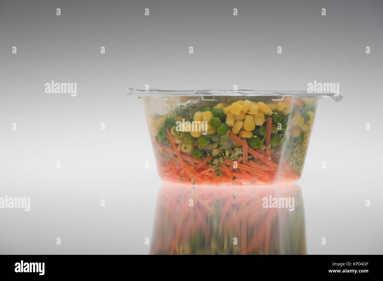 Pronto verdure in contenitore di plastica pronto per mangiare su uno sfondo bianco, piselli, il mais dolce e le carote. Foto Stock