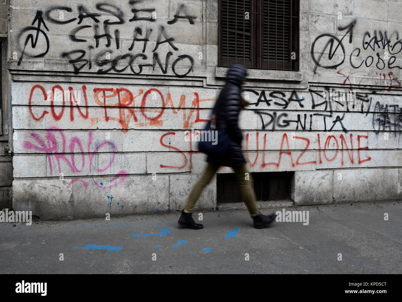 Donna cammina vicino a un muro con scritti politici Foto Stock