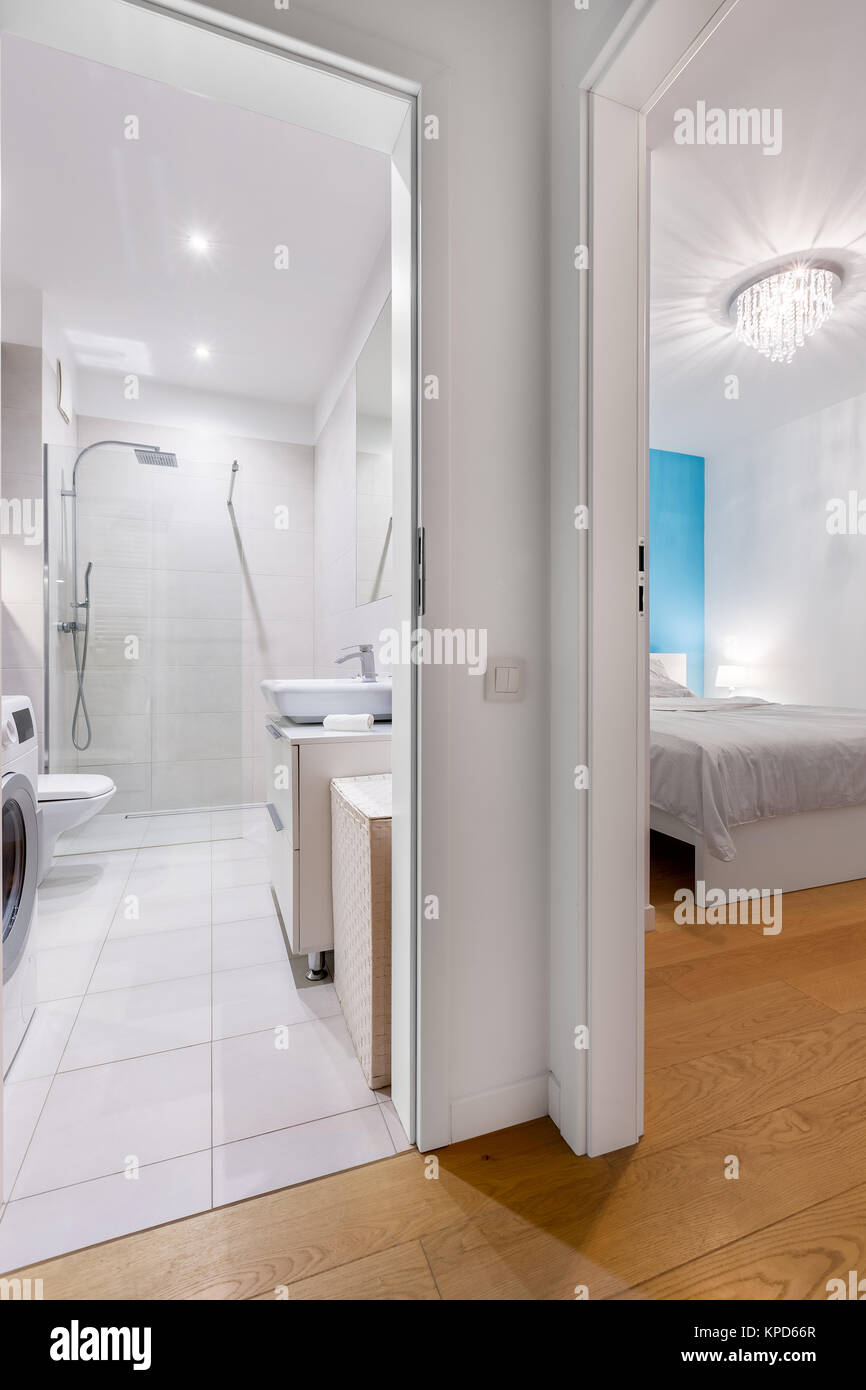 Aprire le porte al grande bagno bianco e camera da letto con parete blu Foto Stock