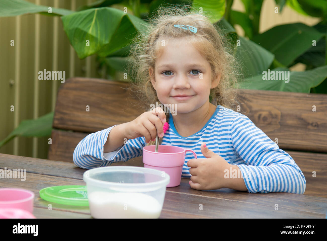 Quattro anni di ragazza nel tè interferisce con lo zucchero per la prima colazione Foto Stock