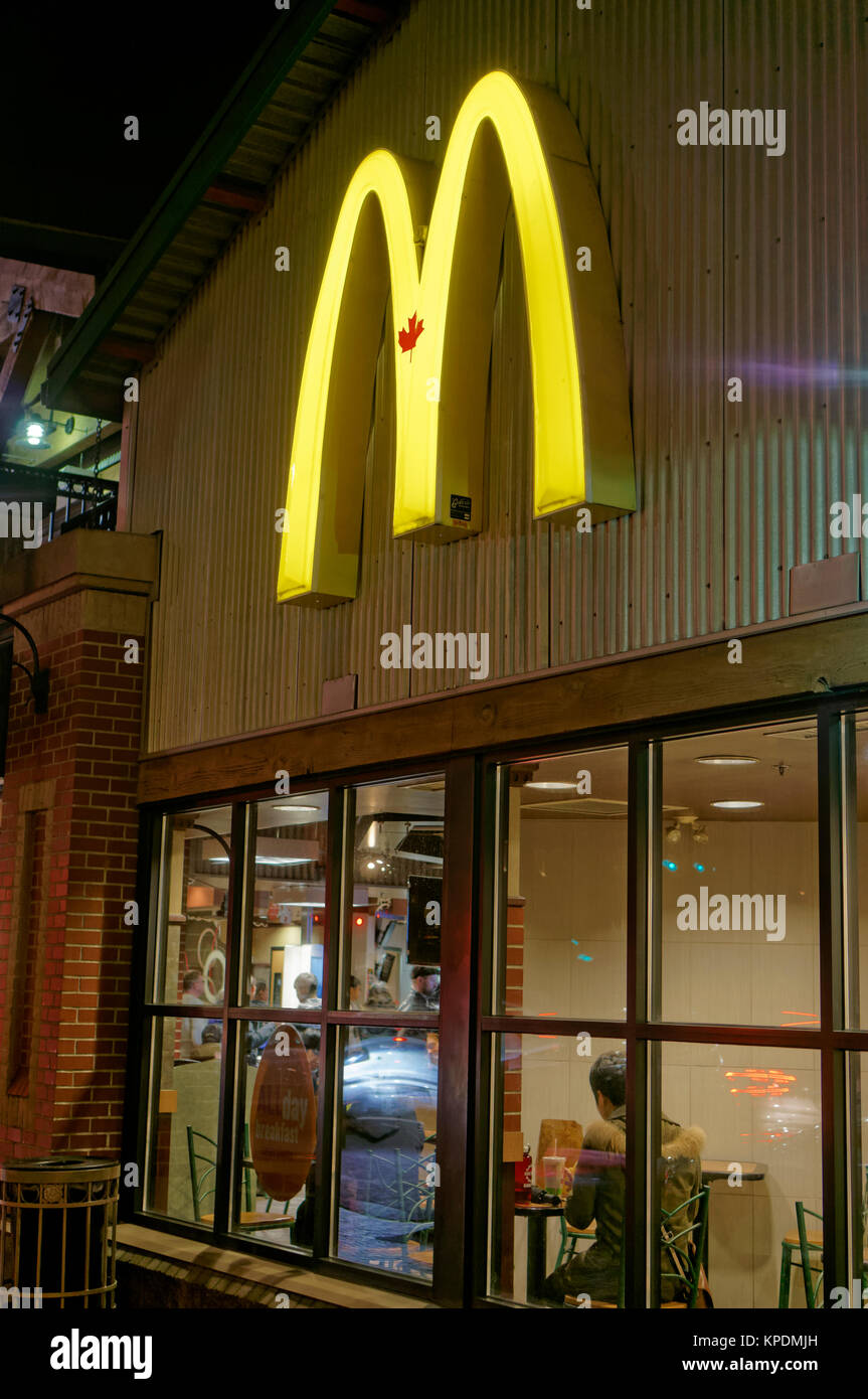 Giovane uomo seduto in un McDonald's ristorante fast food di notte, Vancouver, BC, Canada Foto Stock