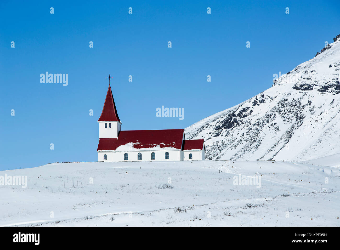 Chiesa di Vik in inverno con montagne innevate in Islanda Foto Stock