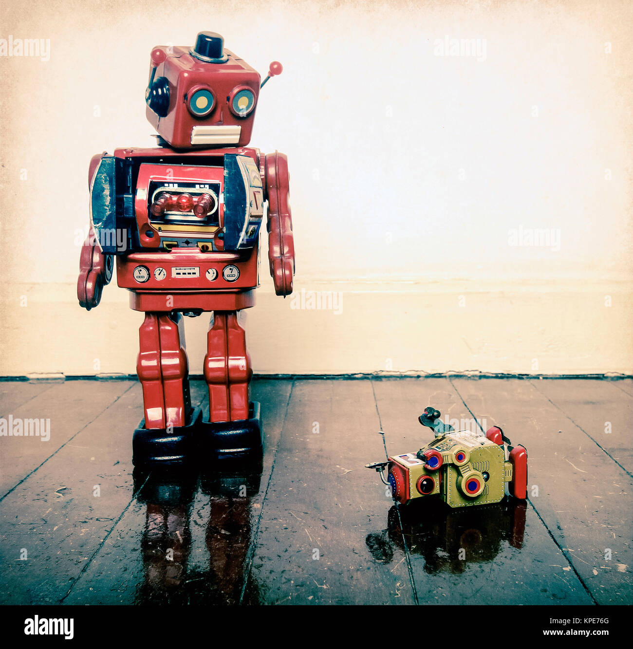 Grande retrò robot giocattolo umilia piccolo robot su un pavimento in legno  con la riflessione Foto stock - Alamy