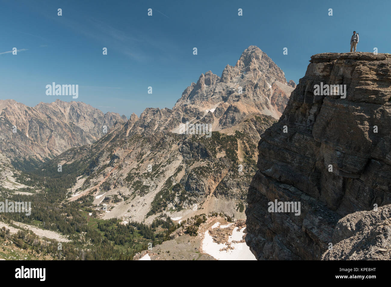 Un escursionista sorge su una scogliera di fronte Grand Teton in Grand Teton National Park, Wyoming Foto Stock