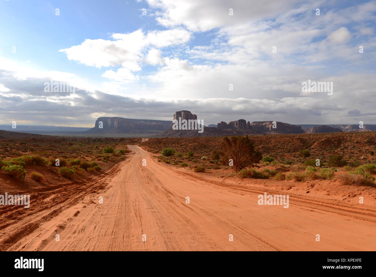 Desert Valley Road - un rosso sterrata strada di sabbia che si estende in una vallata desertica a lontano. Il Monument Valley, Utah e Arizona, Stati Uniti. Foto Stock