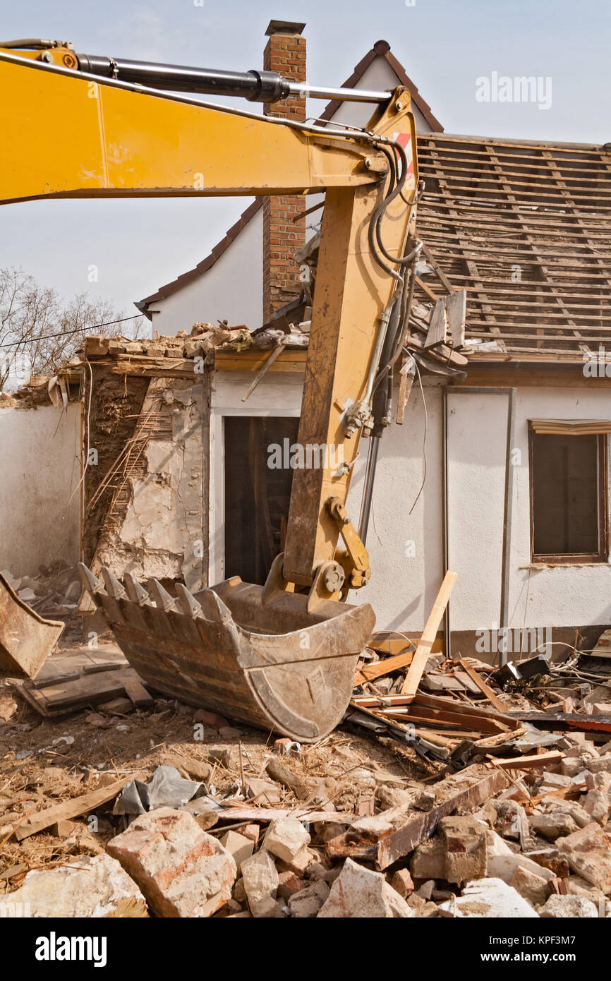 Una grande via hoe escavatore abbattere una vecchia casa Foto Stock