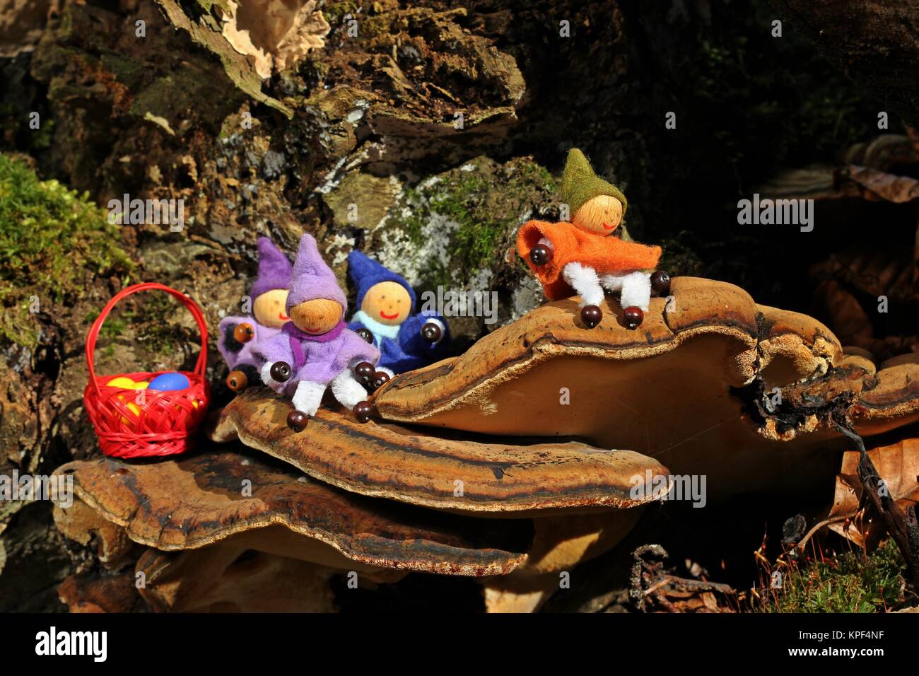 Quattro gnomi con uova di Pasqua siedono su un fungo dell'albero Foto Stock