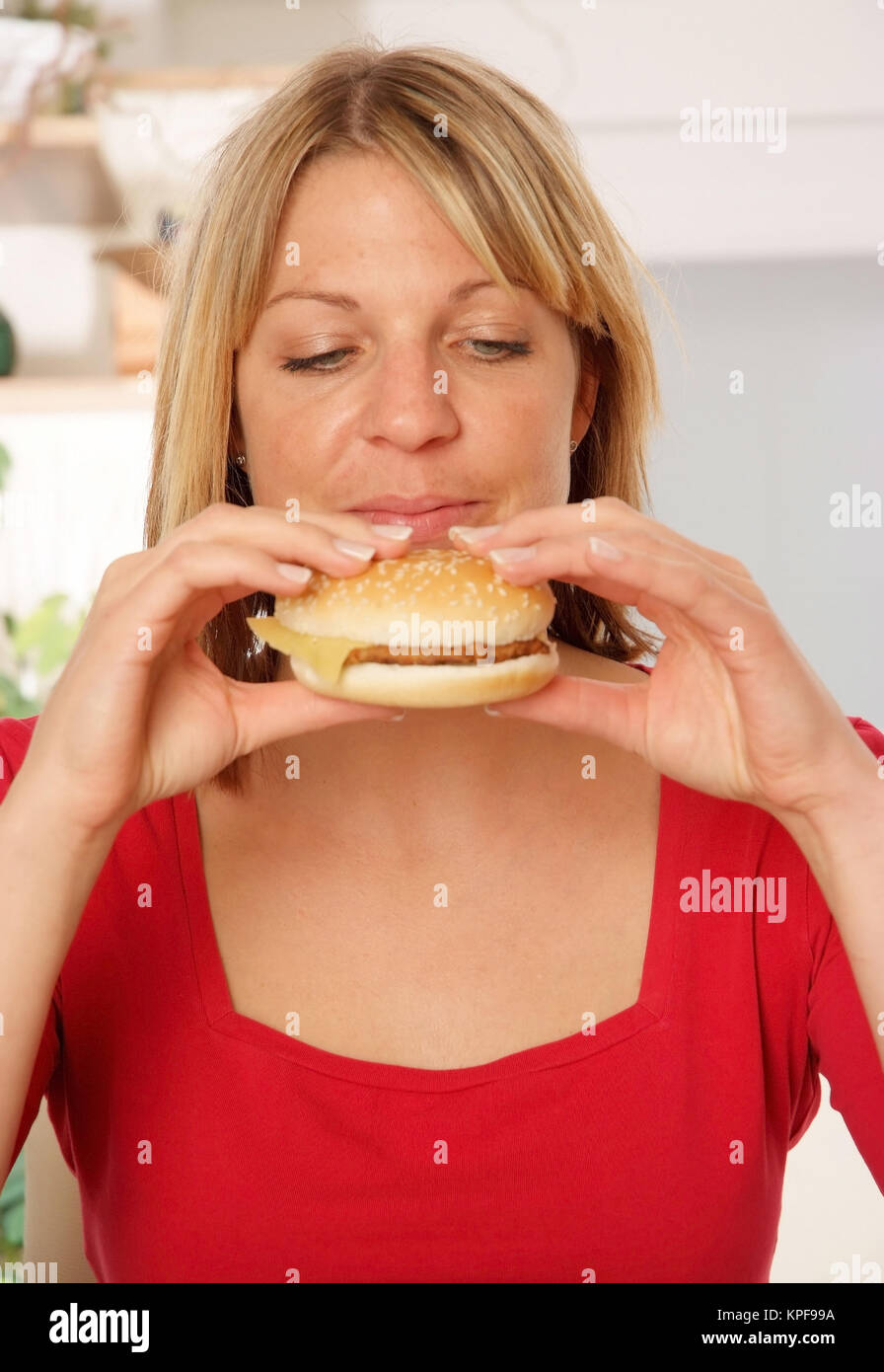 Junge Frau beisst in einen Burger - donna mangia Burger Foto Stock
