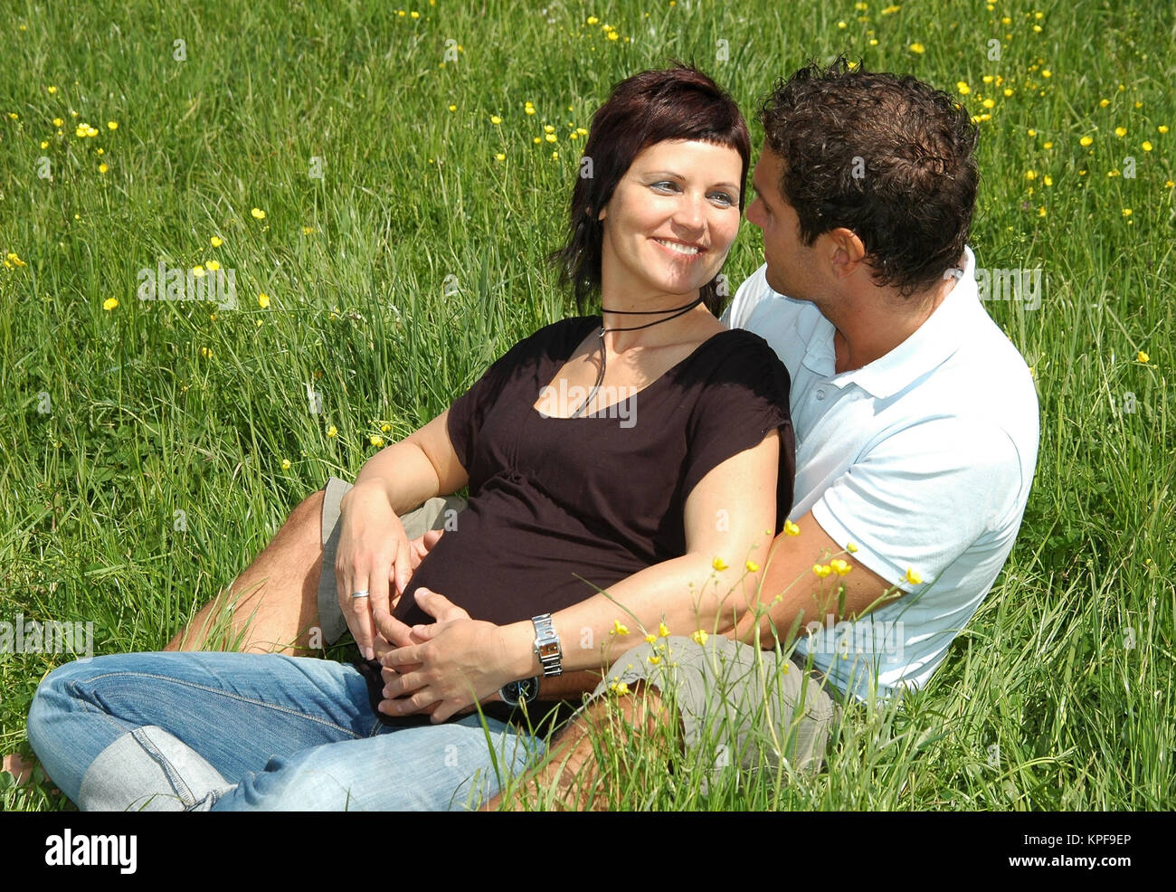 Junge, werdende Eltern sitzen in der Wiese - dei genitori in attesa in Prato Foto Stock