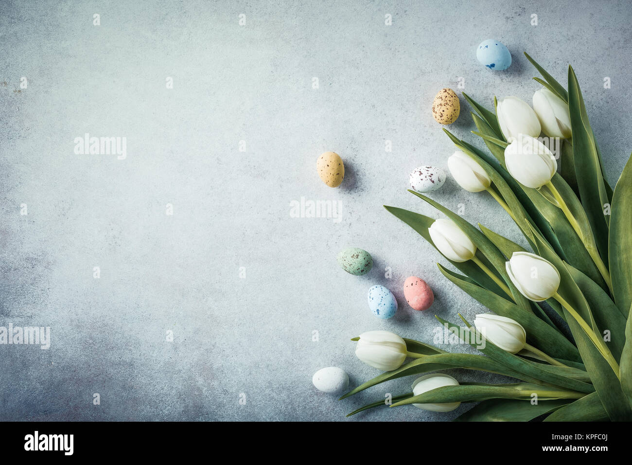 La primavera e a Pasqua sfondo. Tulipani bianco con colorate uova di quaglia. Concetto di vacanza con copia spazio. Foto Stock