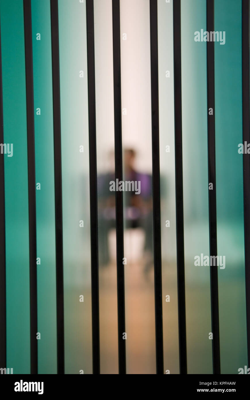 Guardando attraverso diversi fogli di vetro verso una offuscata persona seduta Foto Stock