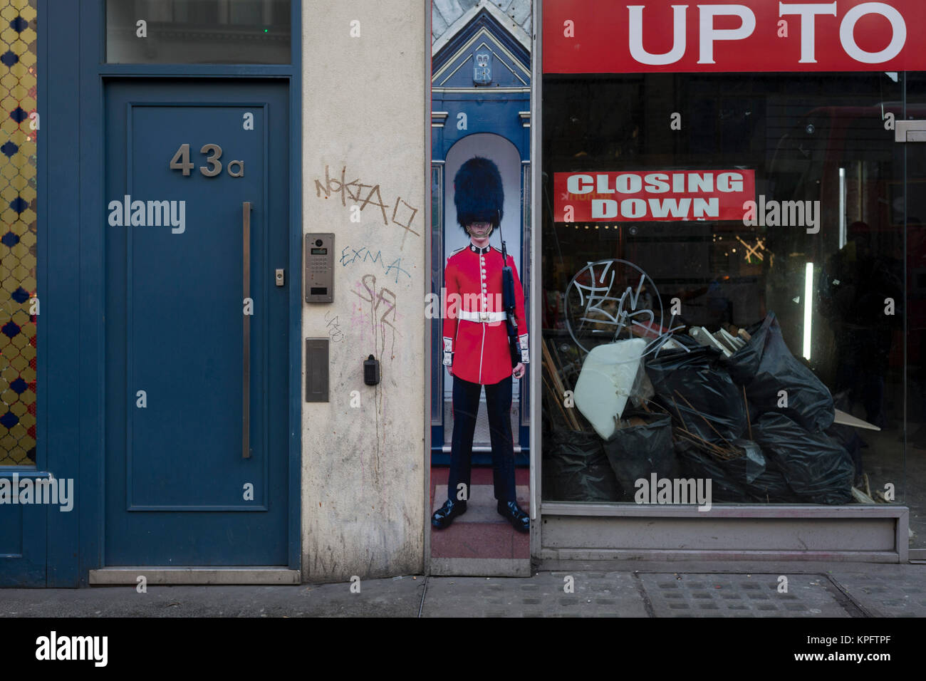 La prospettiva schiacciata di un granatiere guardsman in piedi come sentinella accanto a una porta e un chiuso business - una metafora per Brexit, su Oxford Street, il 12 dicembre 2017, a Londra Inghilterra. Foto Stock