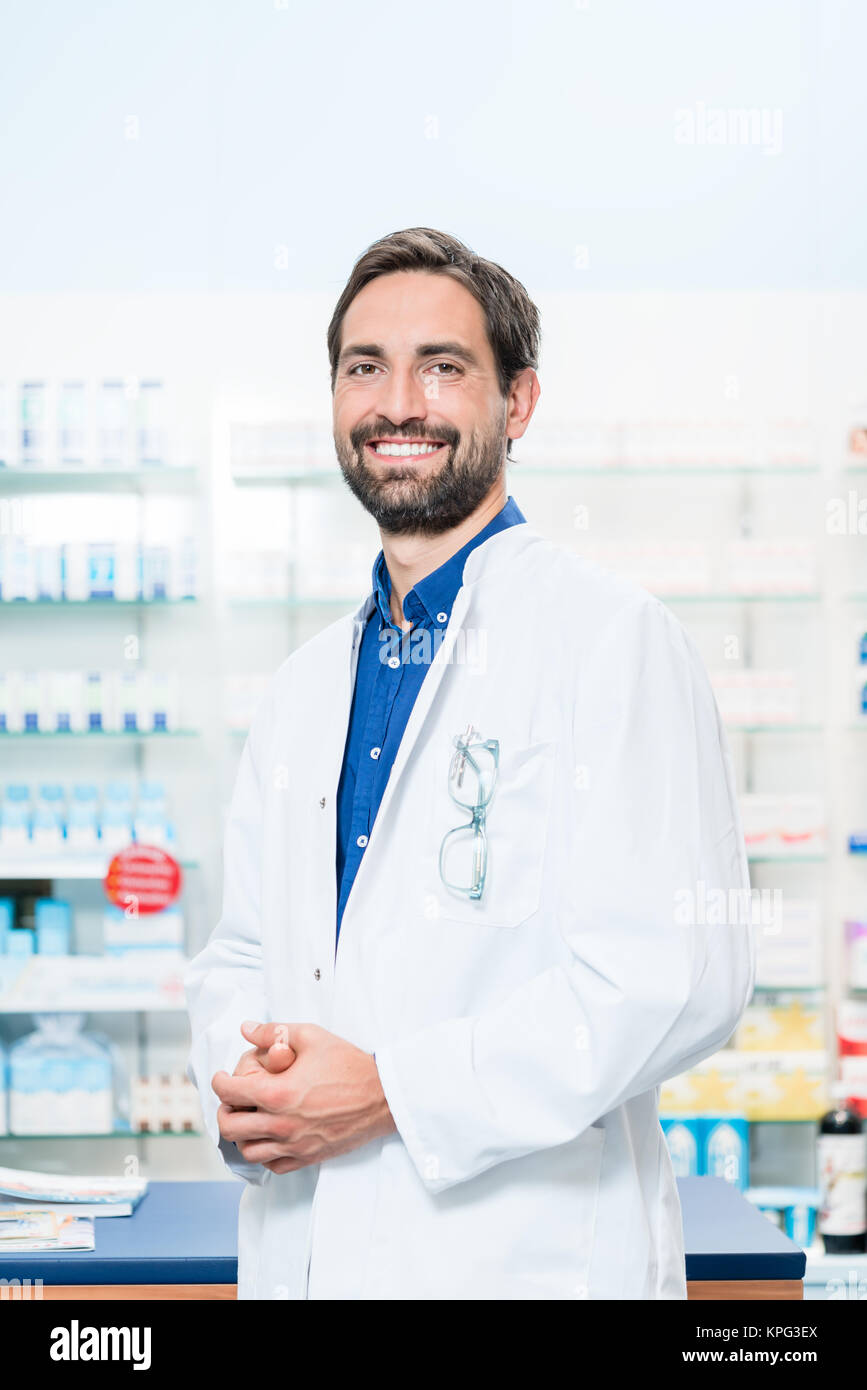 Il farmacista in farmacia sorge nella parte anteriore del ripiano con farmaci Foto Stock