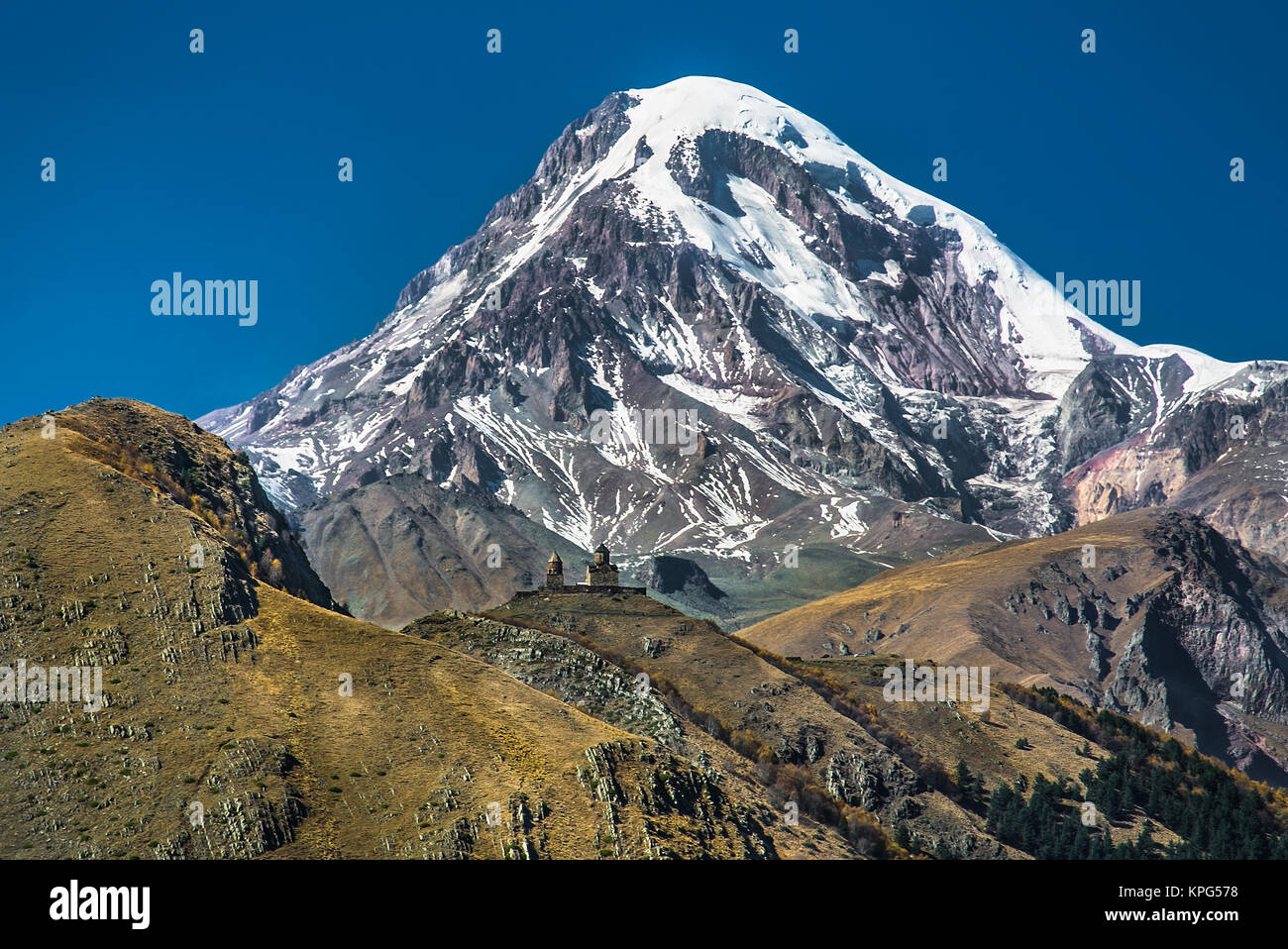 Gergeti Tsminda Sameba di chiesa in Kazbegi (Stepantsminda) villaggio, la Georgia, l'Europa. Foto Stock