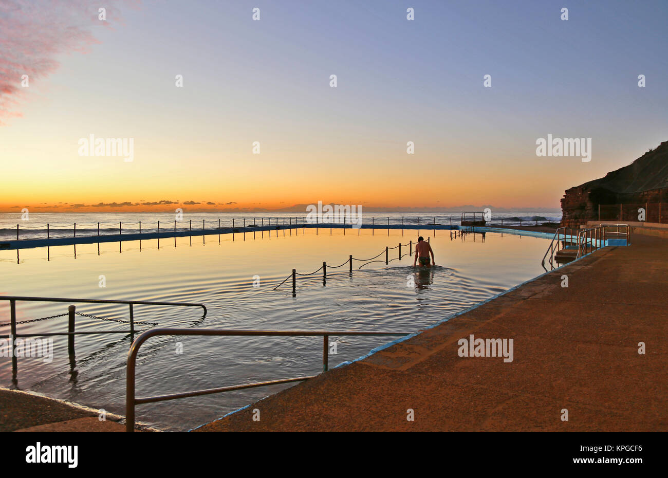 Il vecchio uomo facendo una nuotata mattutina presso sunrise nell'oceano bagni di Bilgola spiaggia, appena a nord di Sydney in Australia NSW. Foto Stock