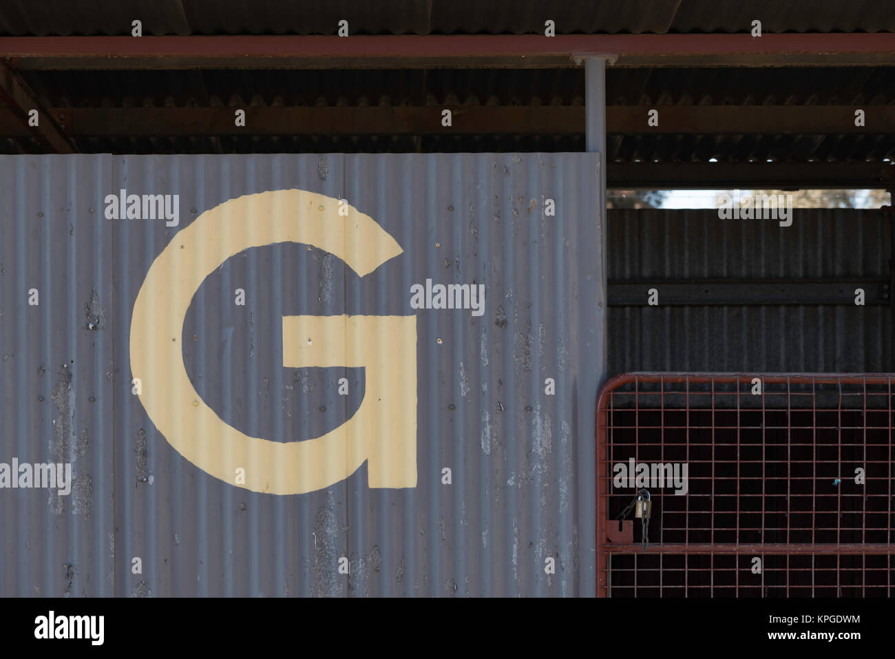 Il lato di un vecchio ferro zincato capannone con una grande lettera G dipinto su di esso Foto Stock