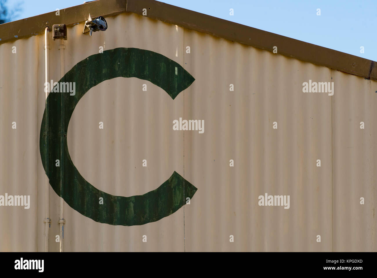 La fine di un vecchio ferro zincato verniciato capannone o edificio con la lettera C dipinto su di esso Foto Stock