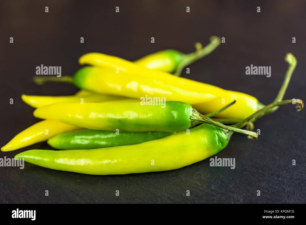 Pila di giallo e i peperoni verdi su sfondo nero lastra di pietra. Foto Stock