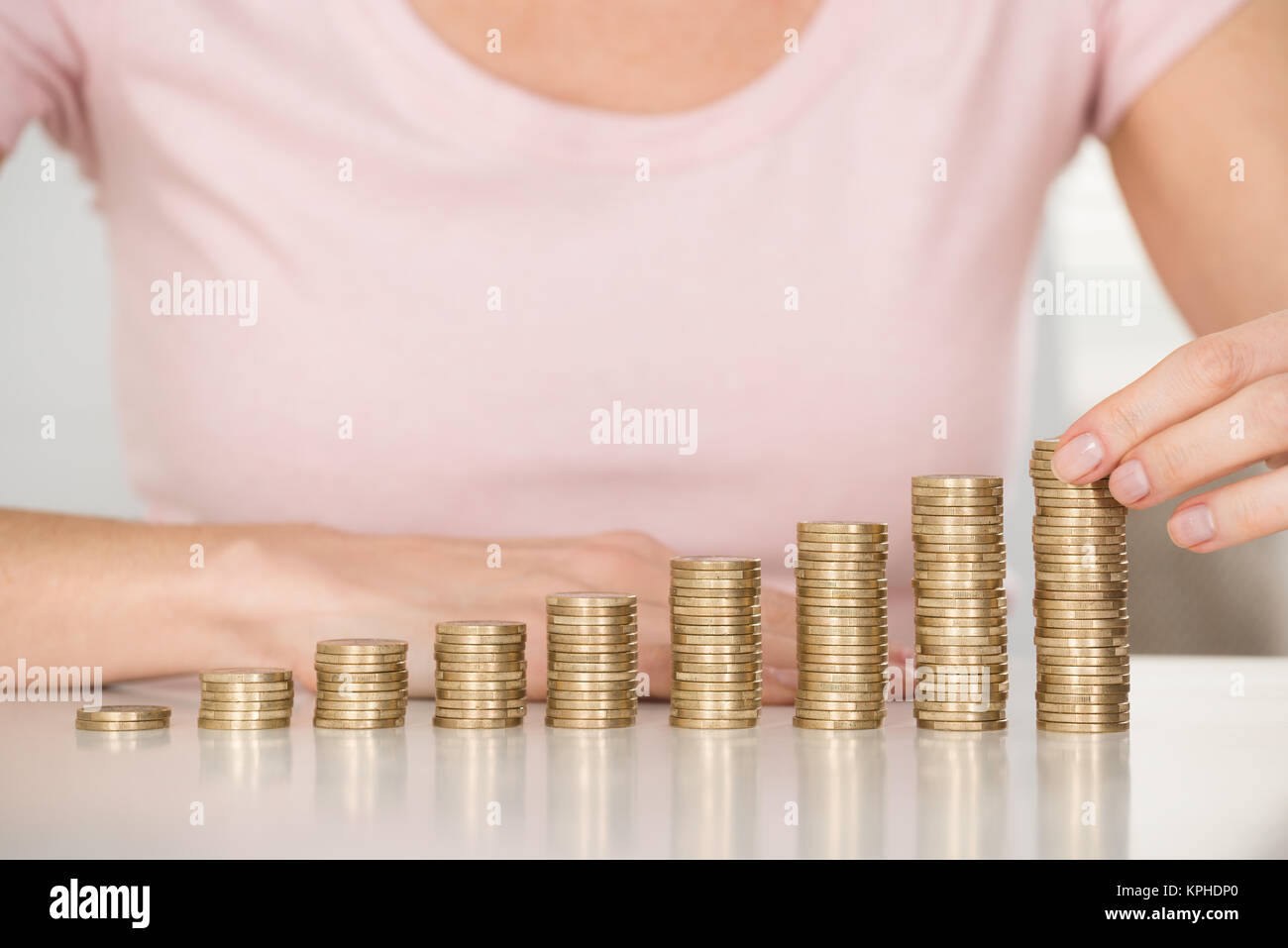 Donna di monete di impilamento al banco Foto Stock