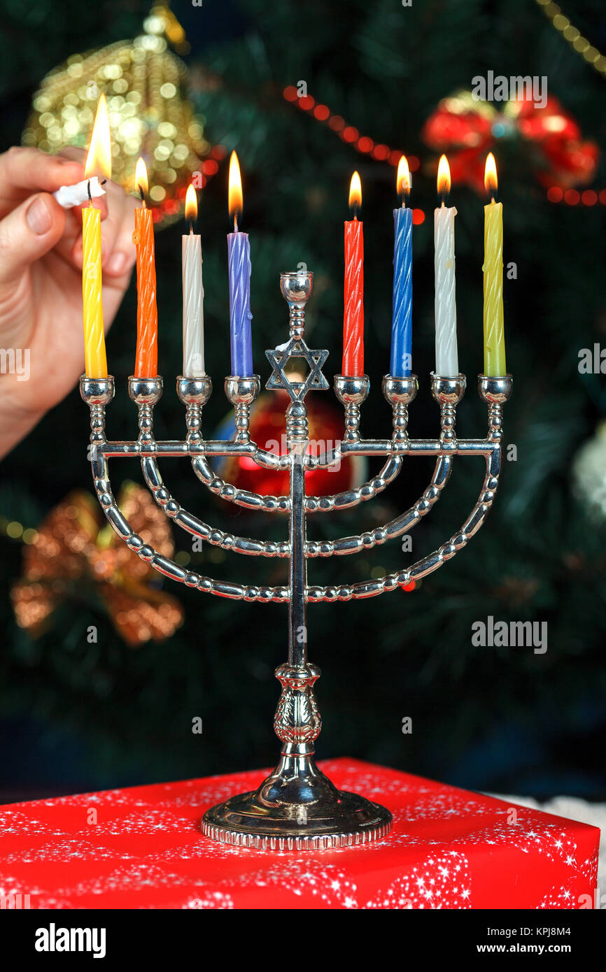 Il Menorah con candele per Hanukkah sullo sfondo del Nuovo Anno Albero. Illuminazione da studio Foto Stock
