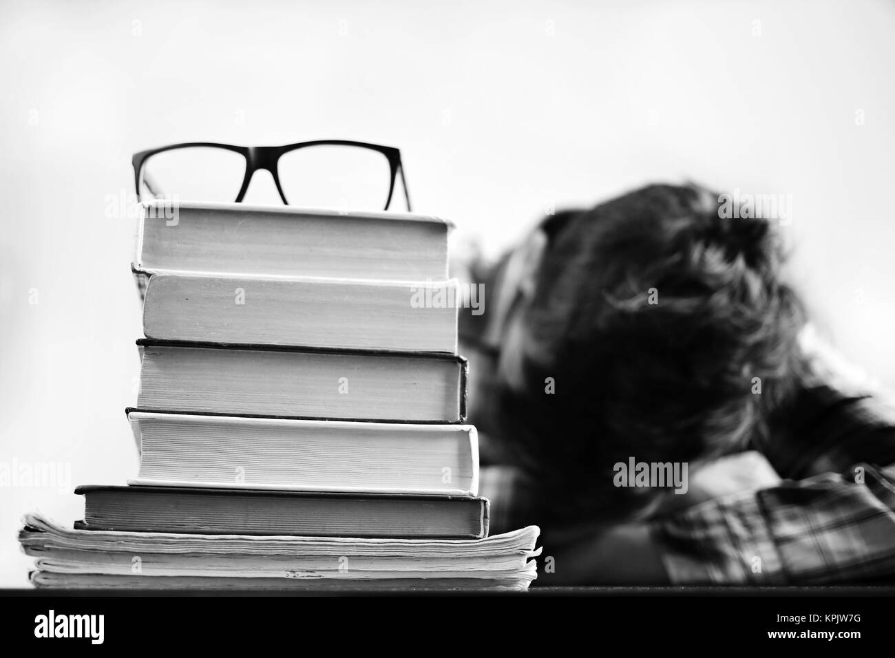 Lo studente con gli occhiali che fanno un lavoro. Studente che studia esame duro e dormiente sui libri. Studiare il concetto di apprendimento. Foto Stock