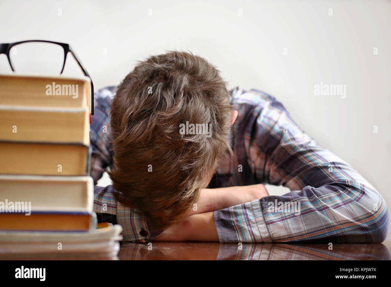 Lo studente con gli occhiali che fanno un lavoro. Studente che studia esame duro e dormiente sui libri. Studiare il concetto di apprendimento. Foto Stock