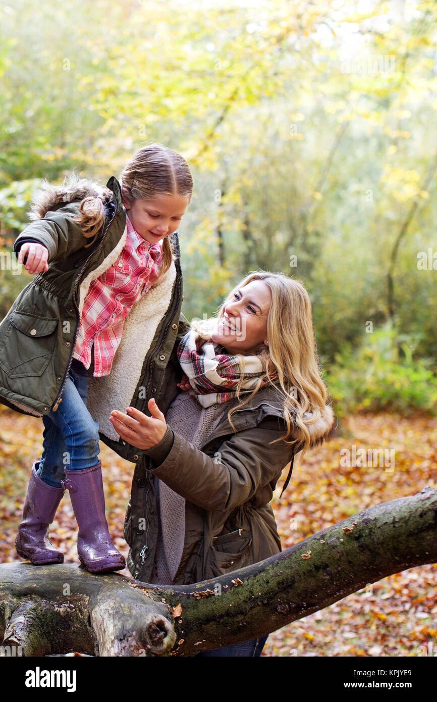 Famiglia giocando su un albero nel bosco in autunno. Foto Stock