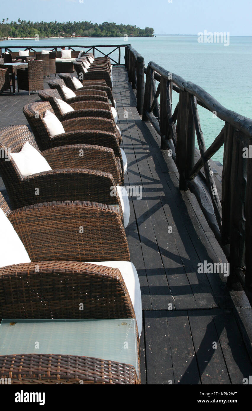 Riga di tessuto di sedie di vimini sul molo, Hotel Sea Cliff, Zanzibar, Tanzania. Foto Stock