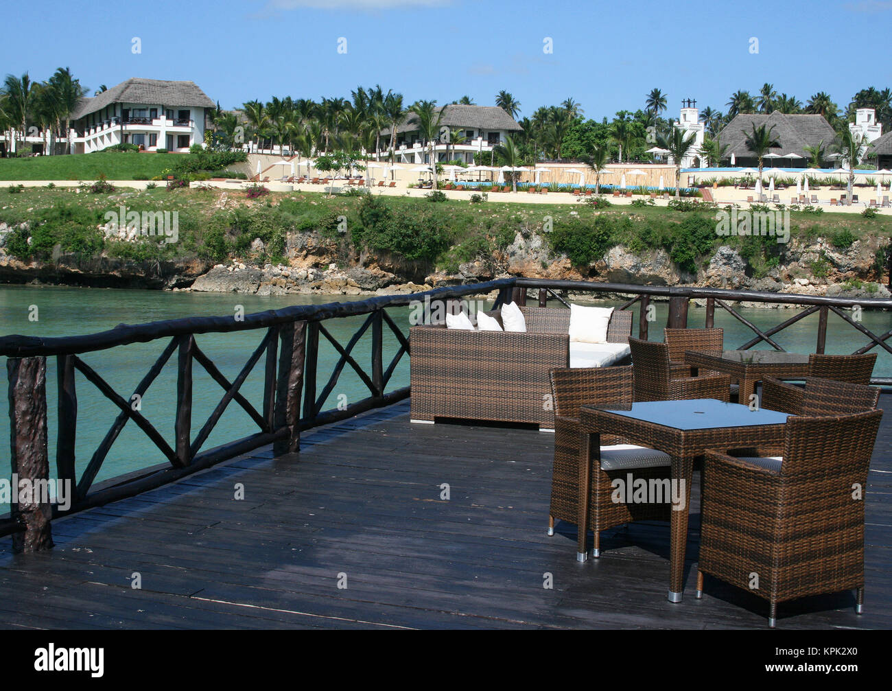 Tessuto di sedie di vimini, la tabella e il lettino sul molo di fronte all'hotel le capanne, Hotel Sea Cliff, Zanzibar, Tanzania. Foto Stock