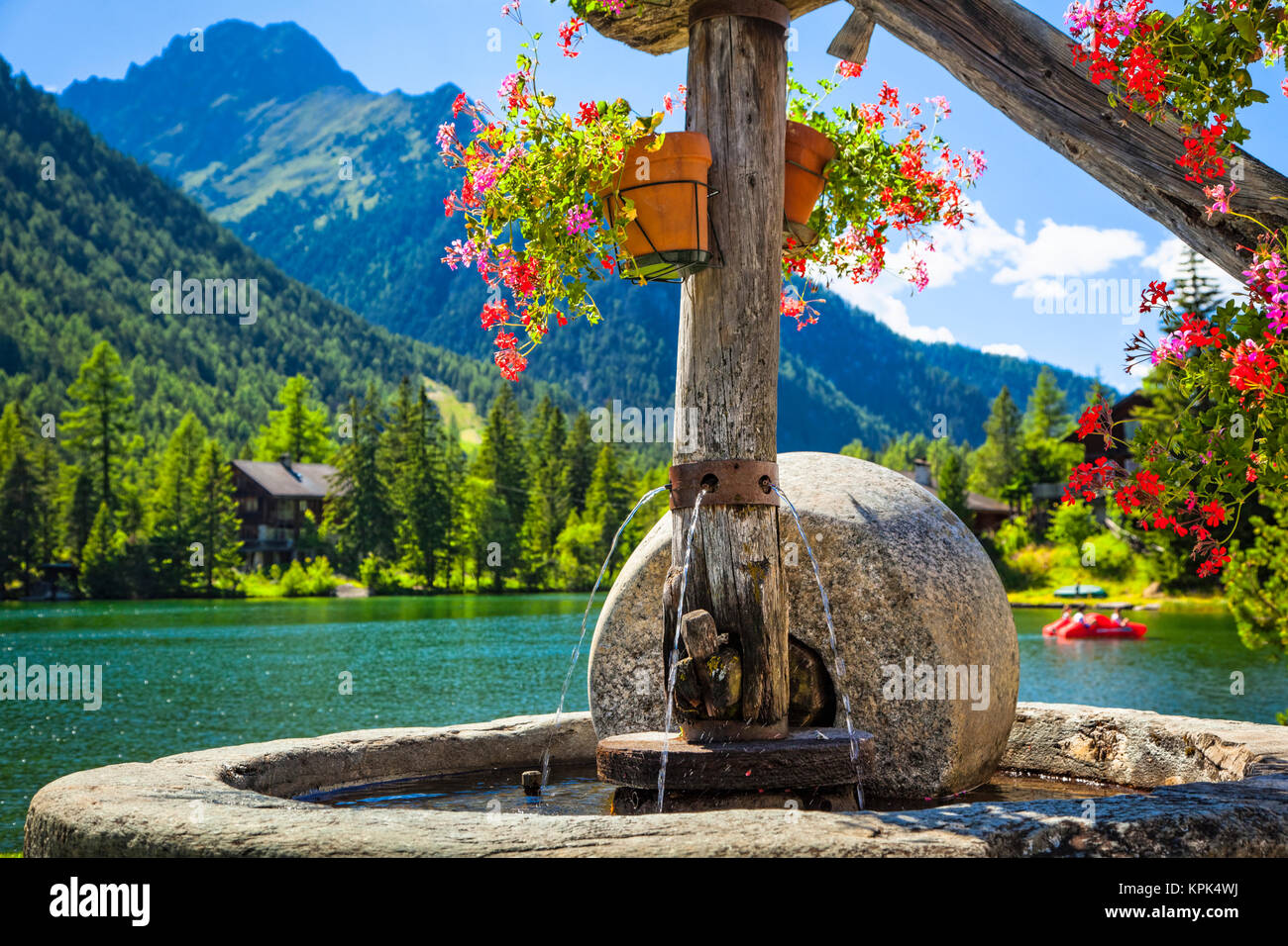 Close-up di una fontana di pietra con vasi di fiori da Champex e la gamma della montagna in background; Champex, Vallese, Svizzera Foto Stock
