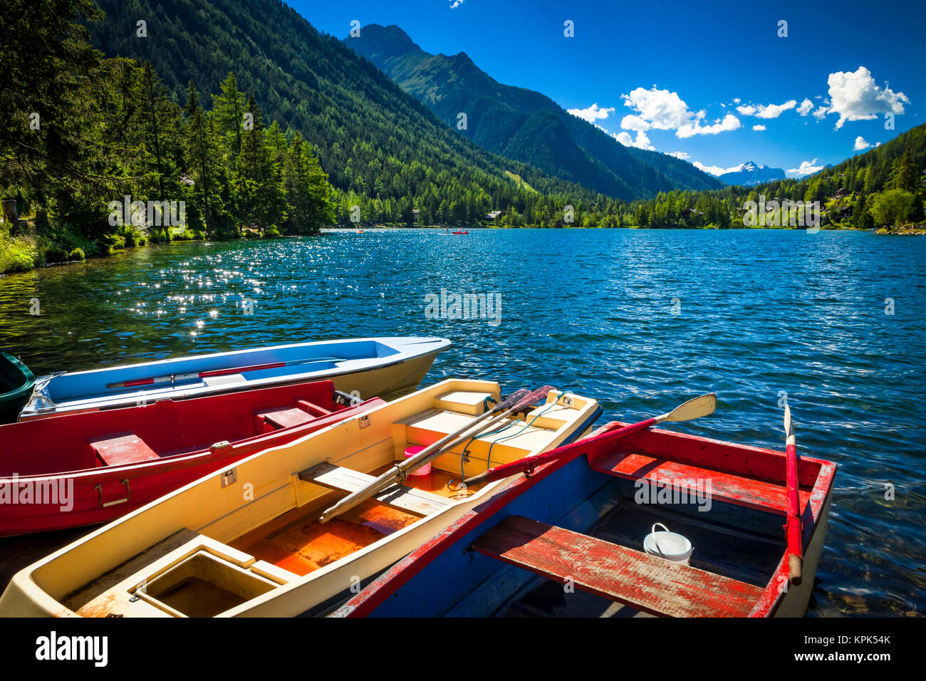 File colorate barche con Champex circondato da montagne sotto il cielo blu, Alpi; Champex, Svizzera Foto Stock