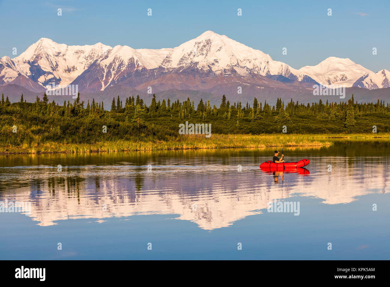 Un uomo attraverso le piastre Donnelly lago in un pacco zattera con Mt. Moffit e l'Alaska Range riflettendo sull'acqua; Alaska, Stati Uniti d'America Foto Stock