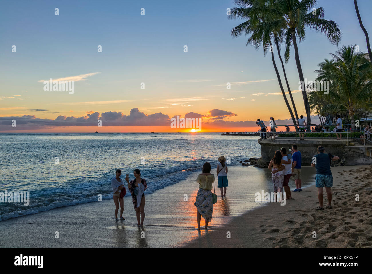 I turisti osservare e fotografare il tramonto sulla spiaggia di Waikiki; Honolulu Oahu, Hawaii, Stati Uniti d'America Foto Stock