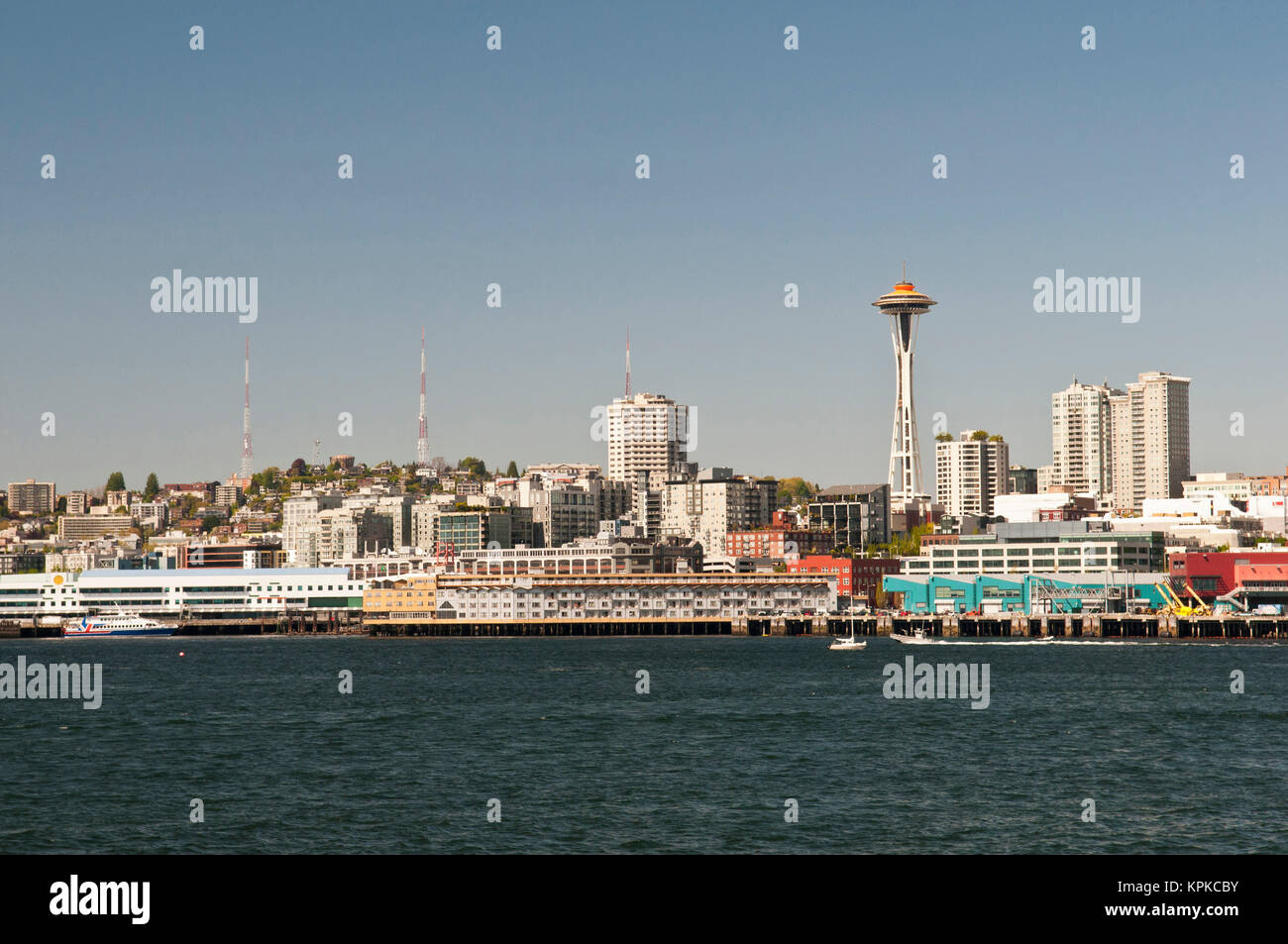 Stati Uniti d'America, WA, Seattle. Skyline del centro e il modo in Alaska waterfront come visto da di Bainbridge traghetto. Lo Space Needle top verniciato di colore arancione per il cinquantesimo anniversario come era stato per il 1962 della fiera del mondo quando è stato costruito. Simbolo iconico di Seattle. Foto Stock